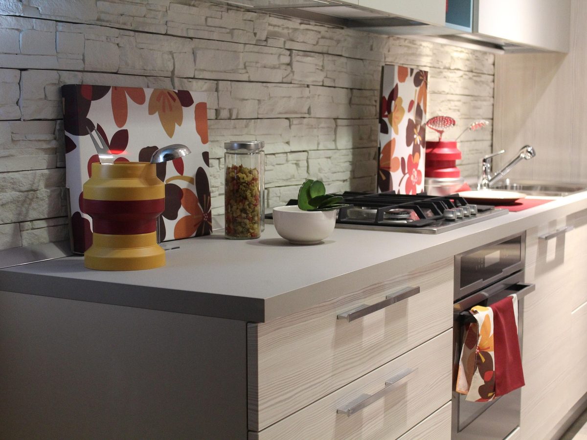 Cuisine linéaire aux portes pâles devant un mur de pierre